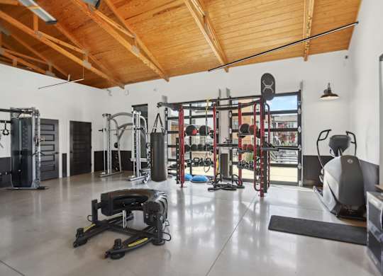 A gym with a variety of equipment including a treadmill, weights, and a television.
