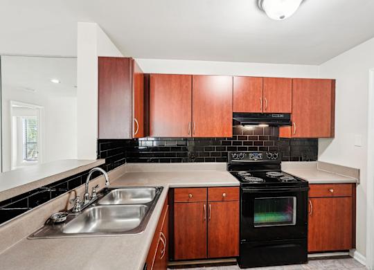 A kitchen with a black appliances and brown cabinets.