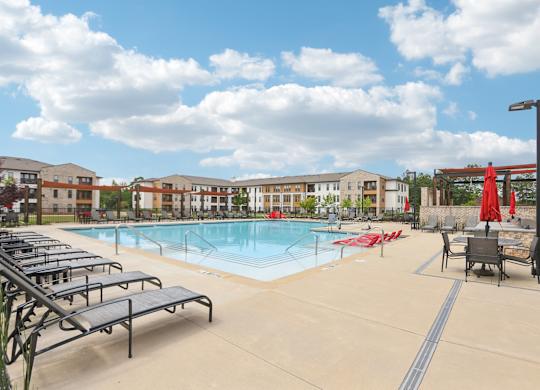 A large swimming pool with many lounge chairs and umbrellas.