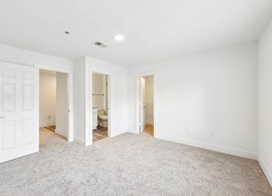 A bed room with a carpeted floor and a door on the left.