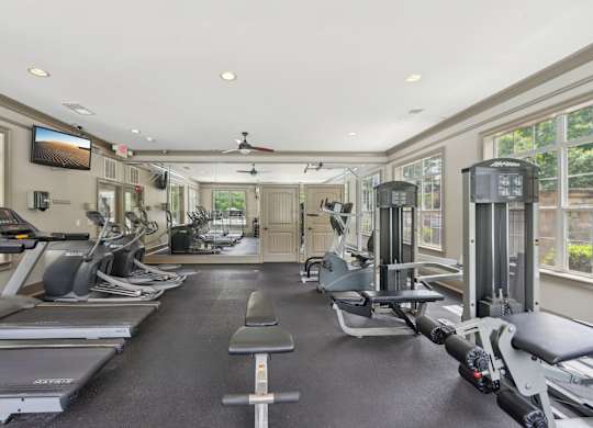 A spacious gym with a variety of equipment including treadmills, elliptical machines, and weight machines.