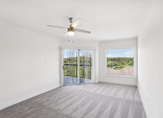 A room with a ceiling fan, carpeted floor, and beautiful view.