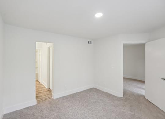 A bedroom with a carpeted floor and white walls.