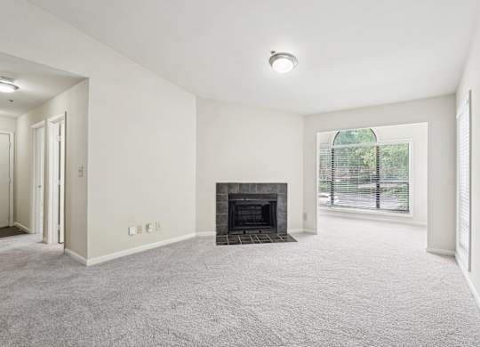 A spacious living room with a fireplace and a sun room
