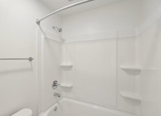 A white bathroom with a toilet, tub, and shower.