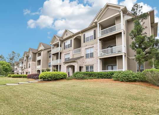 Apartment buildings with balconies and manicured green lawn .