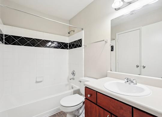 bathroom with brown cabinets and white sink and shower tub