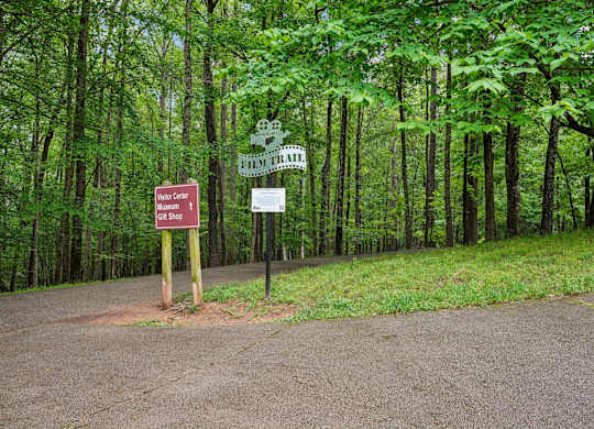 A sign for the Film Trail , Museum, Visitor Center, and gift shop is in front of a wooded area.