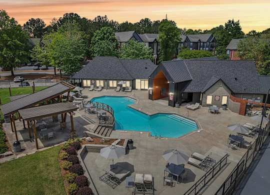 A large outdoor swimming pool surrounded by lounge chairs and umbrellas.