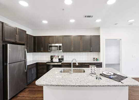 A modern kitchen with dark brown cabinets and stainless steel appliances.