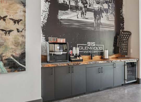 A wall mural in a room with a counter with a coffee machine, beverage fridge, and cabinets.
