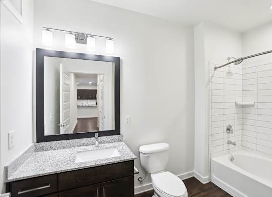A bathroom with a white tub and shower, sink, and toilet.
