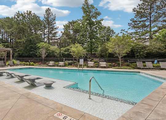 A large outdoor swimming pool surrounded by trees and a building.