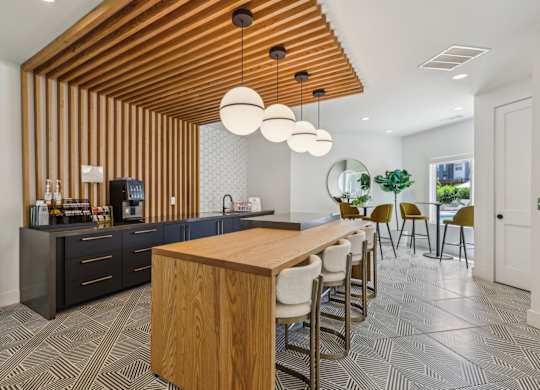 A modern kitchen with a wooden ceiling and a long wooden table.