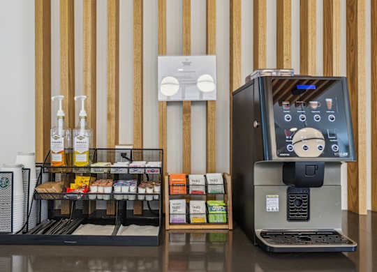 A coffee machine is on a counter next to a display  of syrups, teas, coffees, etc.