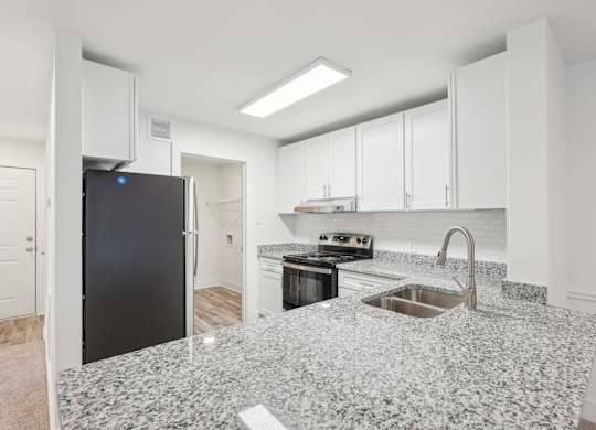 A kitchen with granite countertops, stainless steele appliances, and white cabinets.