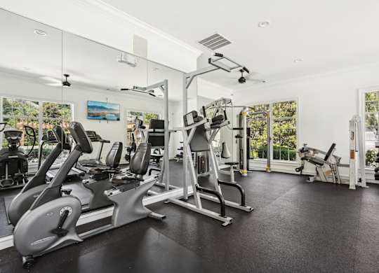 A spacious gym with a variety of equipment including treadmills, stationary bikes, and weight machines.