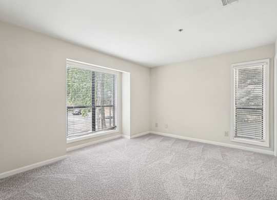 A large bedroom with a carpeted floor and windows