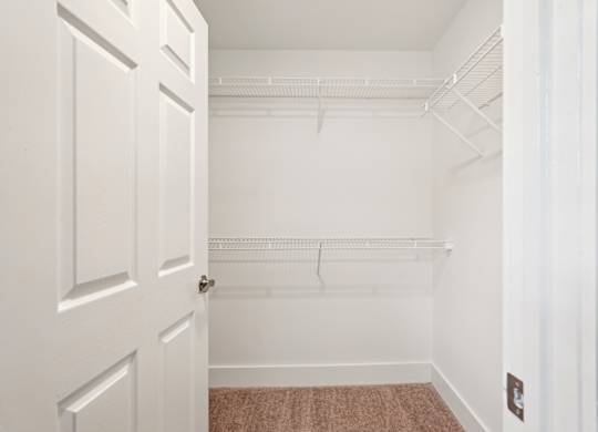 A white door is open to a room with a white wall and a brown carpet.