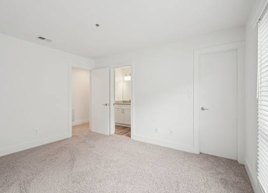 A white room with a carpeted floor and two doors.