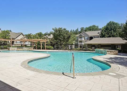 A large outdoor swimming pool surrounded by a stone patio.