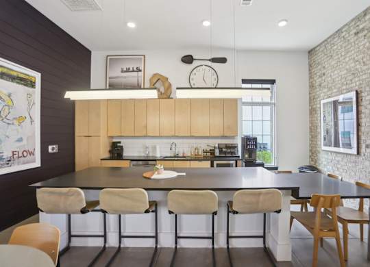 A kitchen with a large island and chairs in resident clubhouse