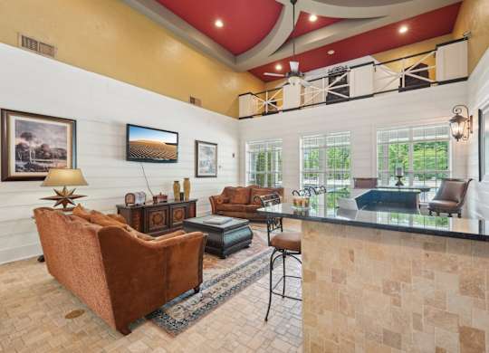 Resident clubhouse with a TV, couch, bar are with stools and a coffee machine station.