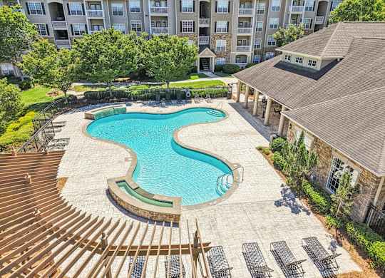 A large swimming pool surrounded by a wooden deck and lounge chairs.