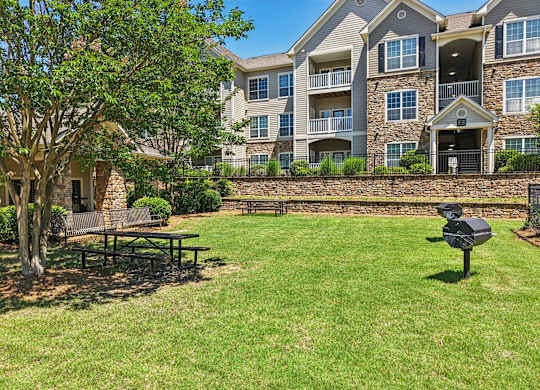 A large grassy area with grills, picnic tables, and benches