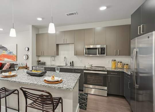 A modern kitchen with a granite countertop and stainless steel appliances.
