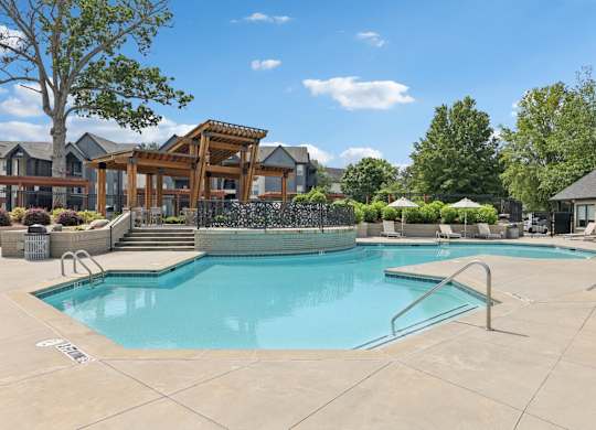 A large swimming pool with a wooden pergola in the background.
