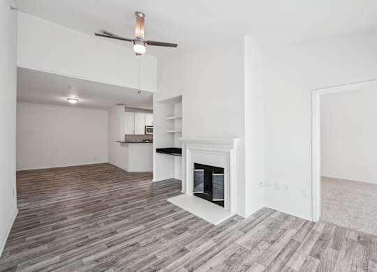 A living room with a fireplace, a ceiling fan, and shelving with a desk area.