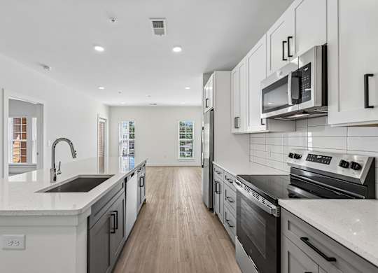 A modern kitchen with white cabinets and stainless steel appliances.