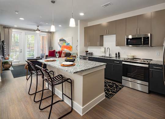 A modern kitchen with granite countertops, neutral two-toned cabinets, and stainless steel appliances.