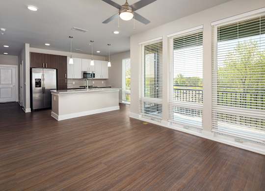 A modern kitchen with wooden floors and white and brown wood cabinets with stainless steel appliances