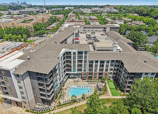 An aerial view of 915 Glenwood apartments with a swimming pool, green area with walking path,  and a parking lot.
