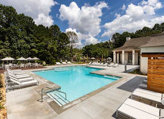 A large swimming pool surrounded by sun loungers and umbrellas.