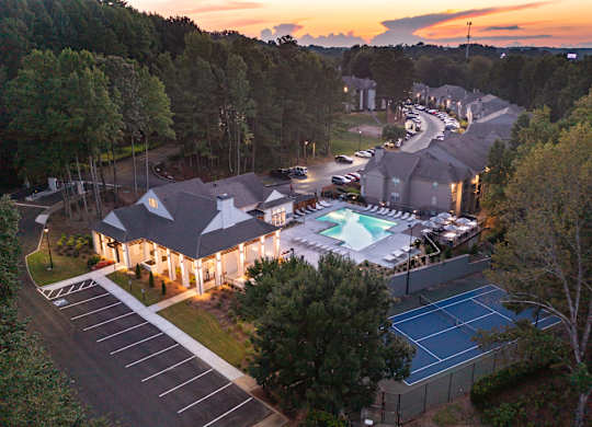 A sunset view of a residential area with a tennis court and pool.