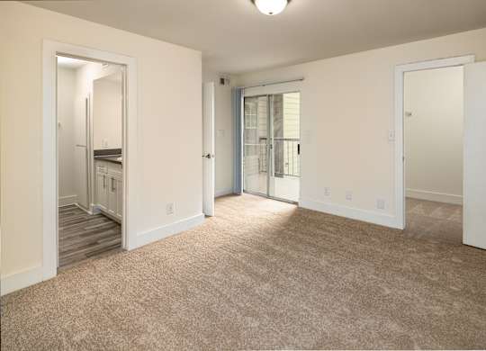 A bedroom with a carpeted floor and a staircase leading to another room.