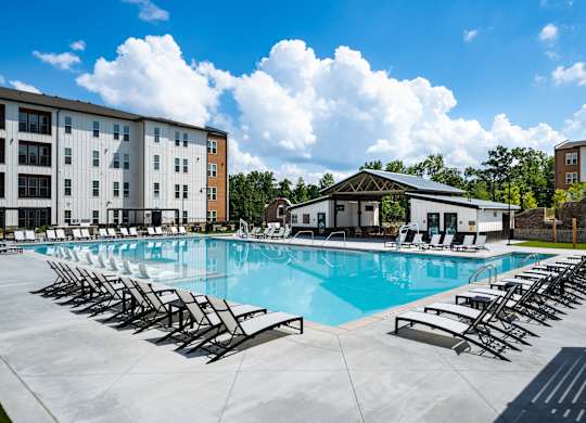 A large swimming pool with lounge chairs and a building in the background.