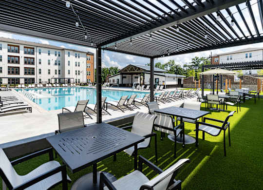 A poolside area with tables and chairs and a building in the background.