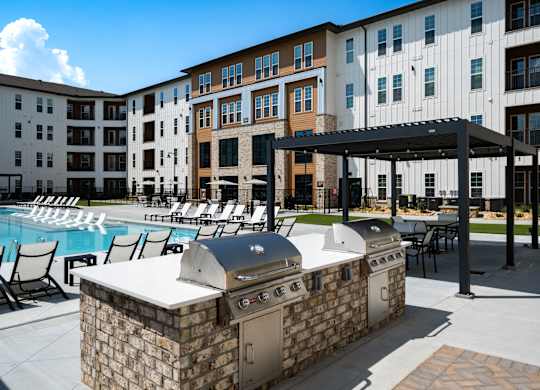 two large outdoor grills are next to the pool and seating areas