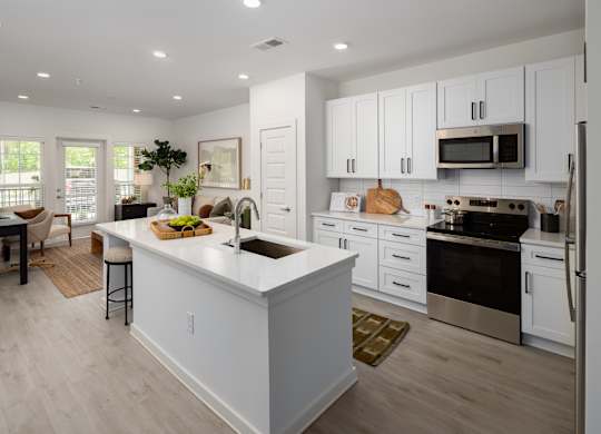 kitchen with quartz countertops, stainless steel appliances, dedicated eat-in island, with a dishwasher, microwave, oven, glass top stove, garbage disposal, and slow close cabinets & drawers