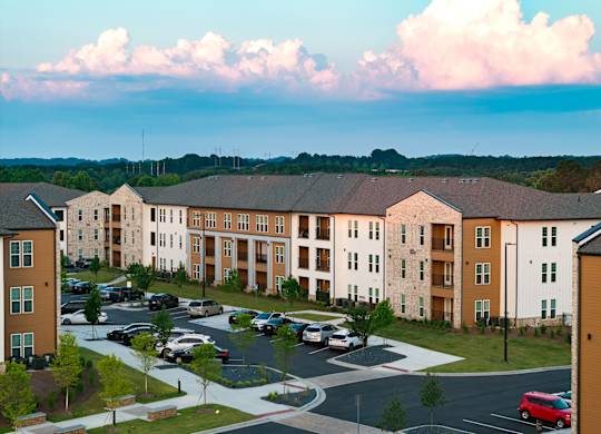 A large apartment complex with a parking lot in front.