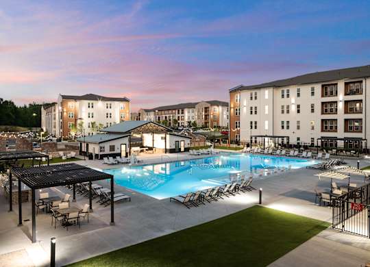 A large swimming pool surrounded by a grassy area and a few chairs.