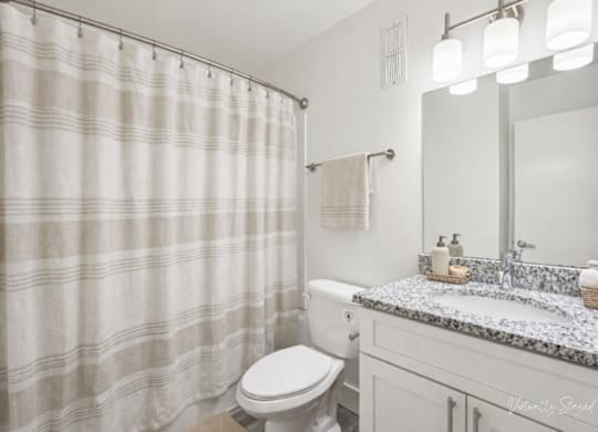 A bathroom with a toilet, sink, and shower curtain.