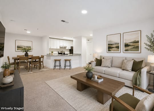 A modern living room with a white couch, wooden coffee table, and a dining table with chairs.