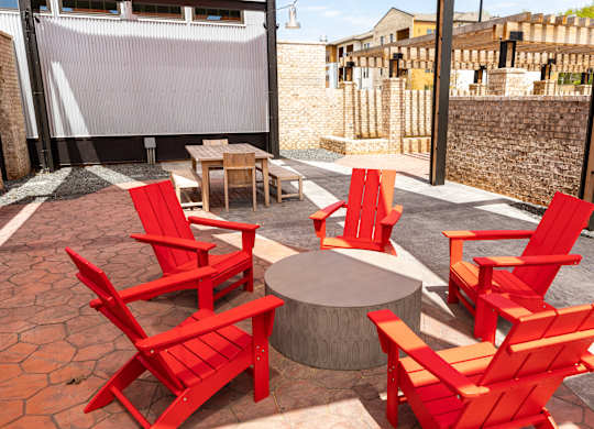 A patio with red chairs and a table.