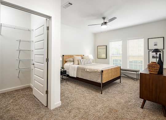 A large bedroom with a bed, dresser, and a ceiling fan.