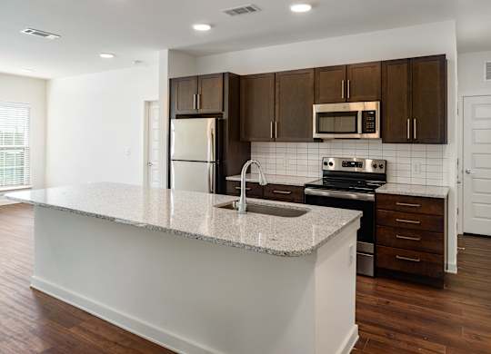 A large kitchen with granite counter top and brown cabinets.